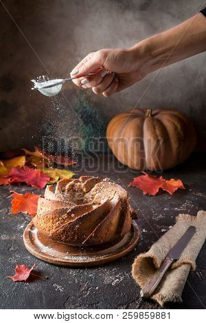 Bundt Cake With Saffron And Rum Covered With White Glaze On Rustic Background With Autumn Decoration