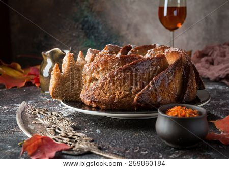Bundt Cake With Saffron And Rum Covered With White Glaze On Rustic Background With Autumn Decoration