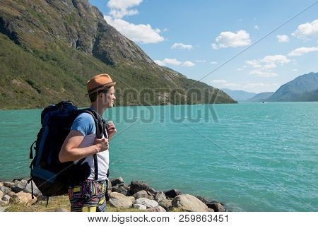 Hiker With Backpack Looking At Gjende Lake In Jotunheimen National Park, Norway