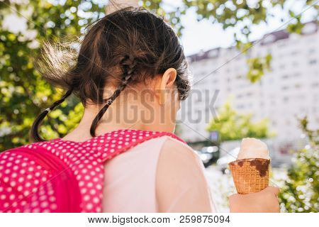 Closeup Rear View Of Cute Little Girl Eating Ice Cream With Blurred Buildings Outdoor. Happy Kid Too