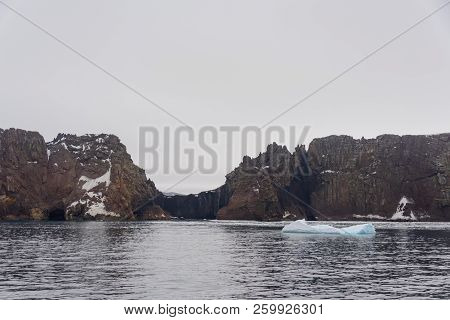 Rocks On Deception Island Beach And Sea With Ice In Antarctica