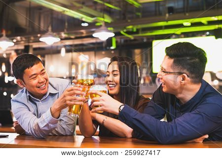 Group Of Happy Asian Friends Or Office Colleague Coworkers Celebrate Toast Beer Pint Together At Pub