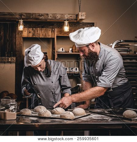 Chef Teaching His Assistant To Bake The Bread In A Bakery.
