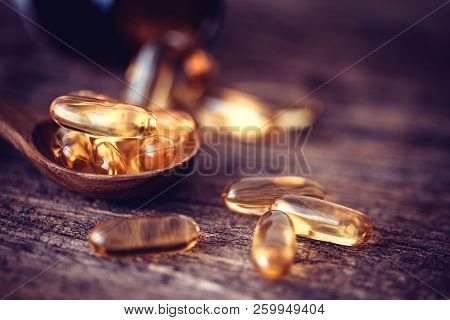 Close Up Vitamin D And Omega 3 Fish Oil Capsules Supplement On Wooden Plate For Good Brain , Heart A