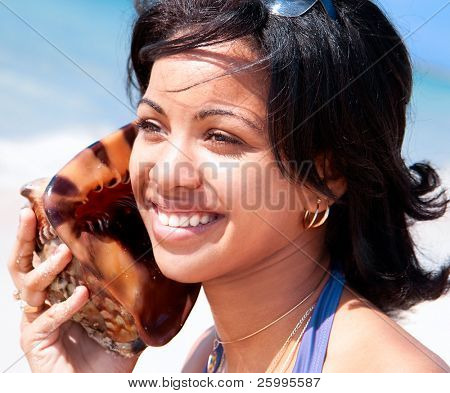 Hermosa mujer Caribe sostienen una caracola a sus oídos