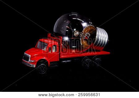 Electric Power Concept Red Truck And Light Bulb On A Black Background