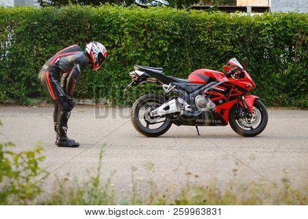 Krasnoyarsk, Russia - August 27, 2018: Beautiful Motorcyclist In Full Gear And Helmet On A Red And B