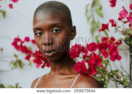 Skinhead woman surrounded by red flowers