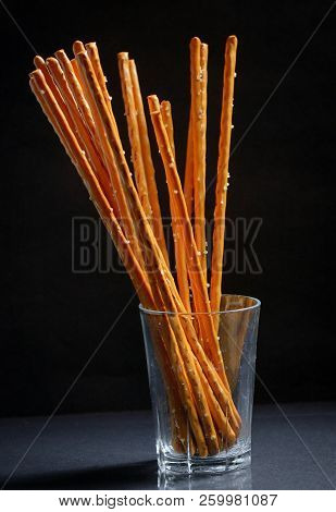 Pretzel Sticks In Small Glass On Black Background