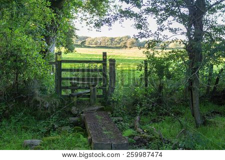 A wooden stile with a way sign on a public right of way on the Gower Peninsula in South Wales, UK. 
