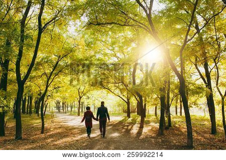 Back Rear View Of Young Couple In Love Woman With Backpack, Man In Casual Warm Clothes Walking By Ha