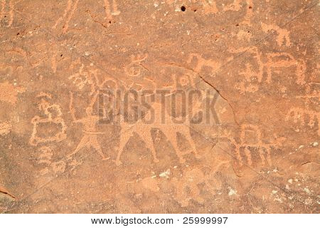 Imagens de pessoas e camelos esculpido em uma parede de rocha em Wadi Rum, um sítio de Património Mundial da UNESCO no Jor