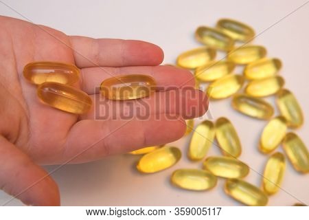 Vitaminen Omega 3 Fish Oil In Capsules In Hand On Beige Background.