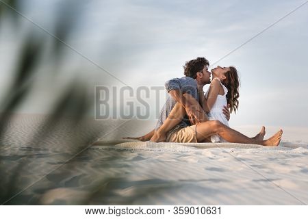 Selective Focus Of Passionate Young Couple Kissing On Blanket On Beach