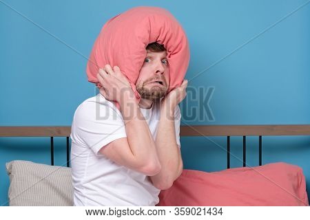 Cauacsian Young Man With Pillow On Head In Bed Being Afraid