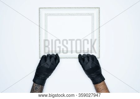 A Man Hand With Black Gloves Holding A Empty(blank) White Photo Frame Isolated On White Background.