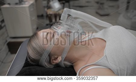 Girl Lies On Bed With Artificial Respiration Mask. Covid-19