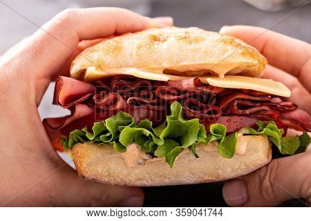 Hands Holding Healthy And Filling Roastbeef Sandwich With Swiss Cheese And Thousand Island Sauce