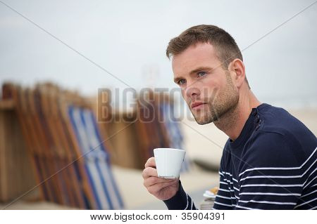 Mand med kaffe på stranden