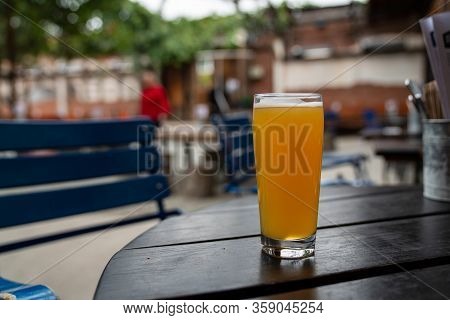 Full Juicy Ipa Beer In Pint Glass On Picnic Table At A Restaurant