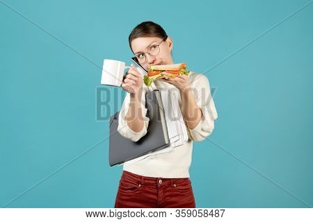 The Junior Office Employee Is Inundated With Work And Eats On The Go. Girl With A Sandwich And Coffe