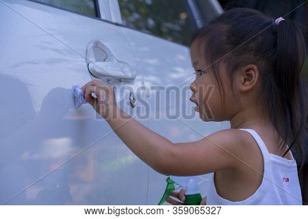 Asian Children Spry Soap To Clean Car Door Handle.