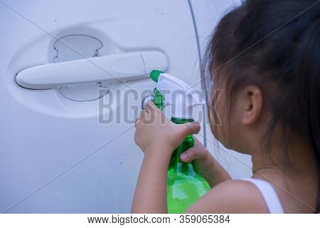 Asian Children Spry Soap To Clean Car Door Handle.