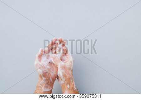 Man Cleaning His Hands Using Liquid Disinfectant Soap Against Light Grey Background.