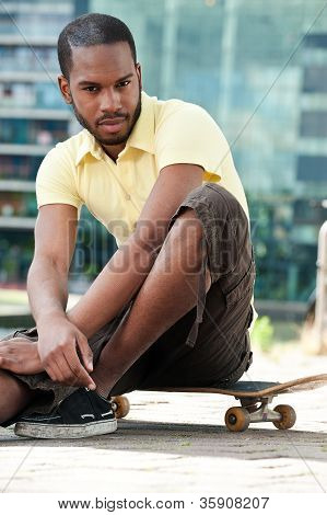 Ung mand sidder på Skateboard og ser på kameraet