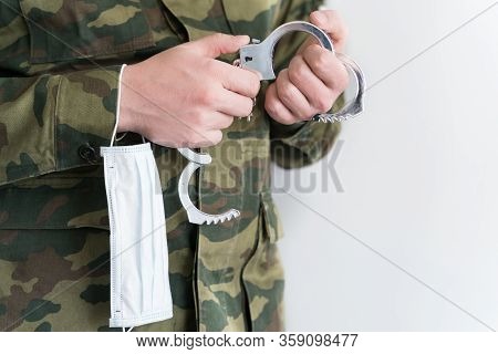 Police Officer With Face Mask And Handcuffs In Khaki Colored Uniform Stops, Arrest Criminal On The S
