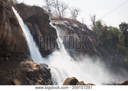 A Huge Waterfall Athirapally In Kerala, India. White Streams Of Water Of The Waterfall Break Into Sm