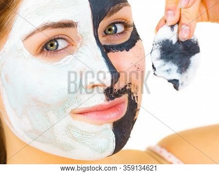 Woman With Clay Carbo Black Mask On One Half Face And White Mud On Second Half. Girl Removing Cosmet