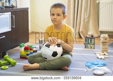 Soccer Ball In A Medical Mask. Activities At Home With Your Children During Home Coronavirus Quarant