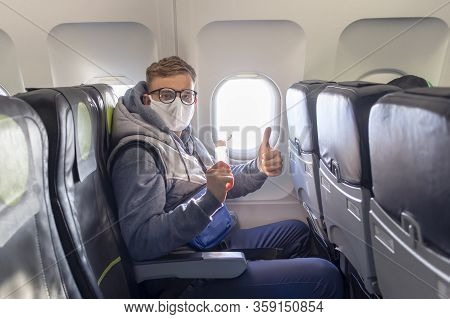 Man On Airplane Show Thumb Up In Glasses, Medical Protective Sterile Mask On His Face Sitting On Pla