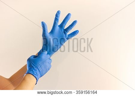 A Hand Wearing Protective Medical Glove With Another Hand Holding It On White Background. Protection