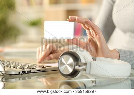 Close Up Of Woman Hand Buying Music Online With Blank Credit Card On Laptop With Headphones On A Des