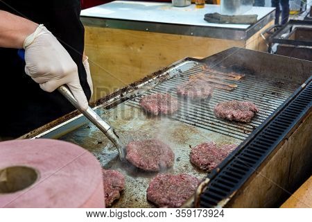 Chef Preparing Delicious Burgers And Flipping Them On Grill.