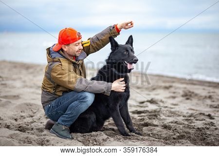 German Black Shepherd With Its Owner On The Sandy Beatch Of Black Sea
