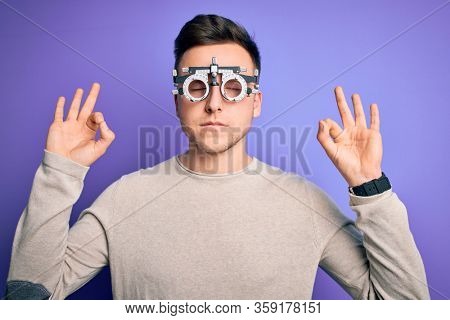 Young handsome caucasian man wearing optometrical glasses over purple background relax and smiling with eyes closed doing meditation gesture with fingers. Yoga concept.