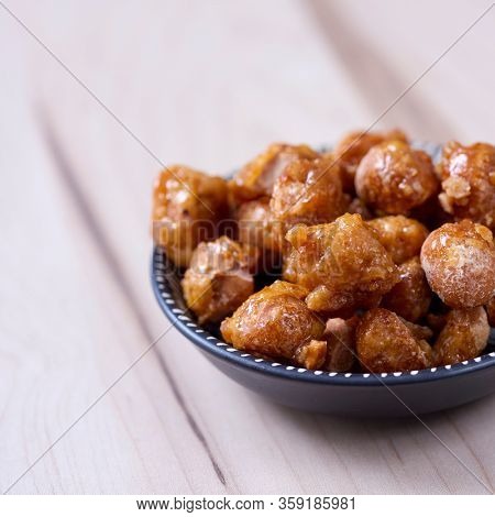 closeup of a plate with some nueces de macadamia garrapinadas, spanish candied macadamia nuts, on a wooden table
