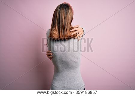 Young beautiful teenager girl pregnant expecting baby over isolated pink background Hugging oneself happy and positive from backwards. Self love and self care