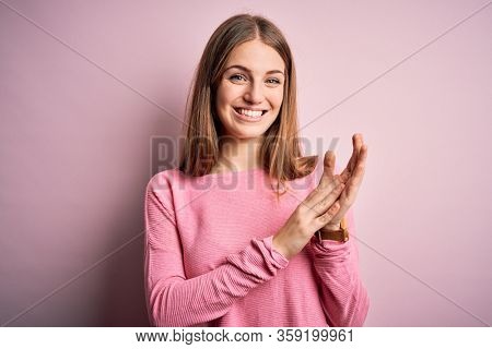 Young beautiful redhead woman wearing casual sweater over isolated pink background clapping and applauding happy and joyful, smiling proud hands together