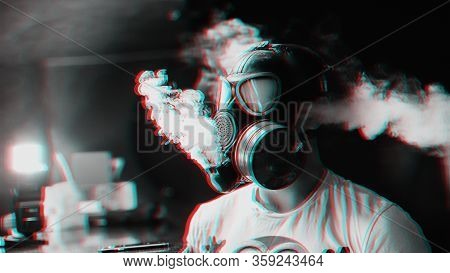Man In A Gas Mask Smokes A Hookah And Breathes A Cloud Of Tobacco Smoke