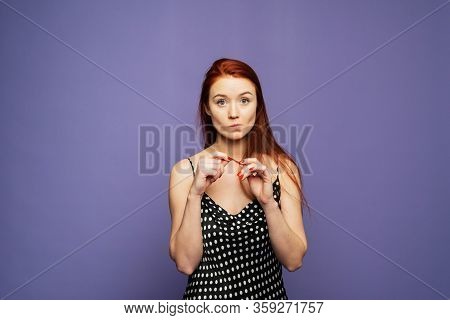 An Embarrassed And Surprised Pretty Woman Stands On A Lilac Background. Template For Your Advertisem