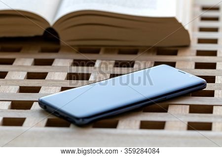 Brech/ Belgium - April 1 2020: A Portrait Of A Smartphone Lying On A Wooden Table Top With In The Ba