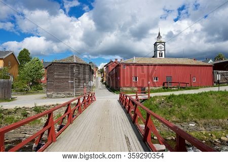 Roros, Norway - June 24, 2013: View To The Traditional Wooden Houses, Bridge And Church Bell Tower O