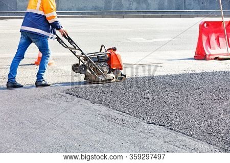 Worker Road Service Use Vibratory Plate Compactor Compacting Asphalt At Road Repair Site.