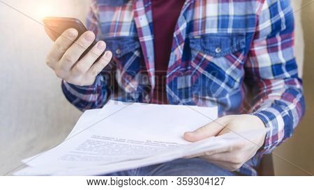 Man Wearing Checkered Shirt Works With Documents At Home