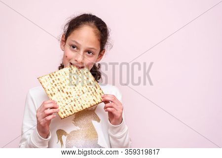 Portrait Of The Cute Teenager Girl Holding Matzah. Jewish Child Eating Matzo Unleavened Bread In Jew
