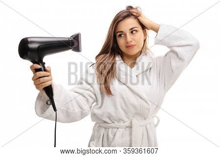 Young woman in a bathrobe blowdrying her hair isolated on white background